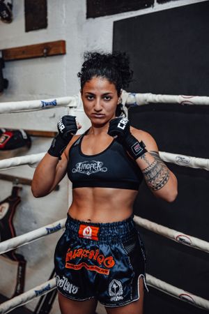 Fighter in black sports gear demonstrating boxing stance in training ring.