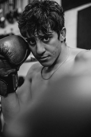 Moody black and white close-up of boxer with gloves during training.