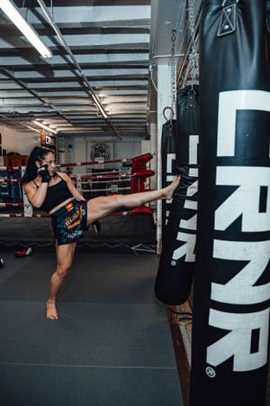 Fighter demonstrating powerful side kicks on heavy bags in spacious gym.