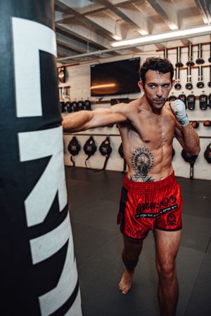 Fighter in red shorts demonstrating dynamic boxing movements in gym setting.