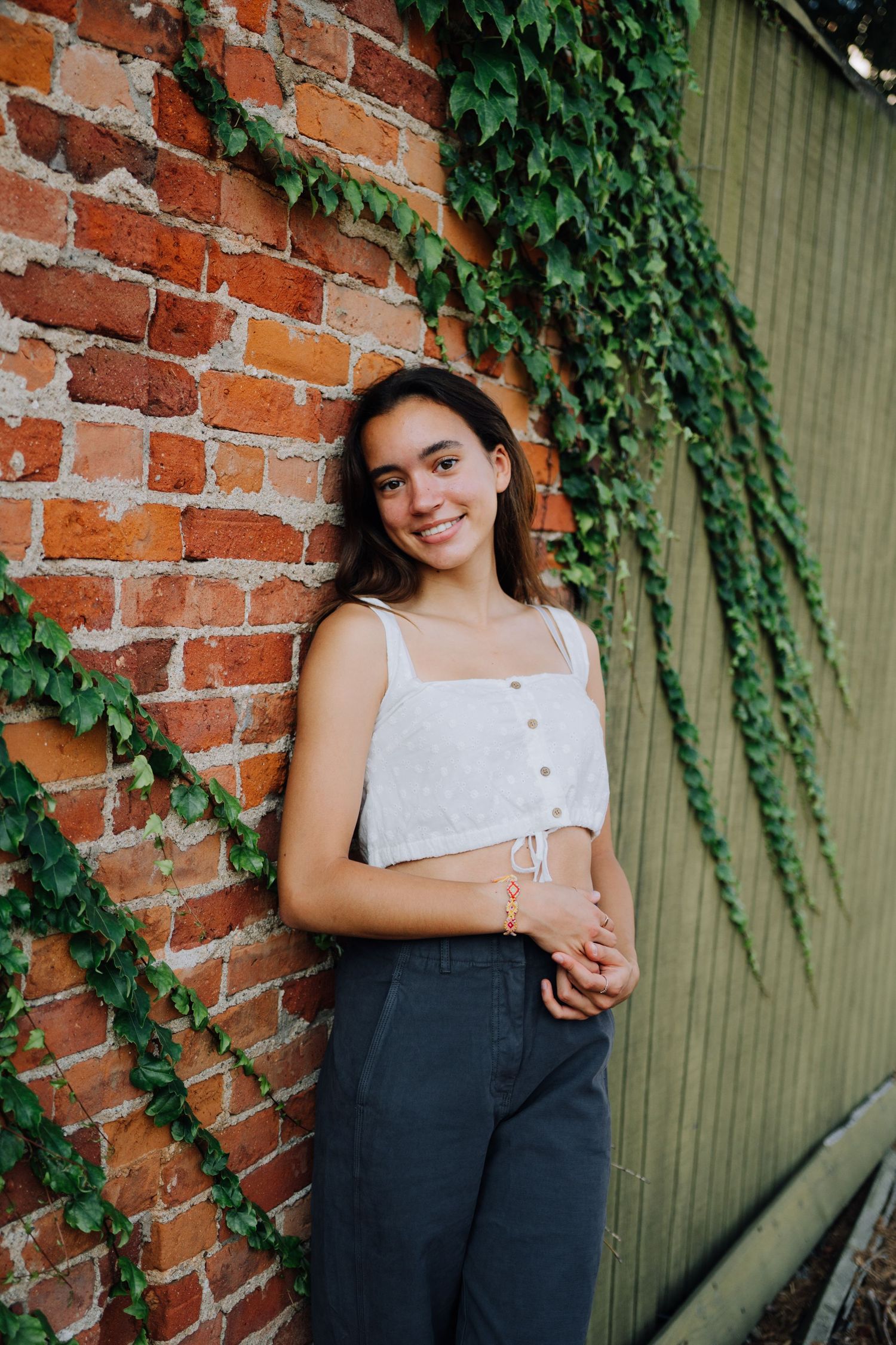 Portraits against rustic brick wall with hanging ivy vines.
