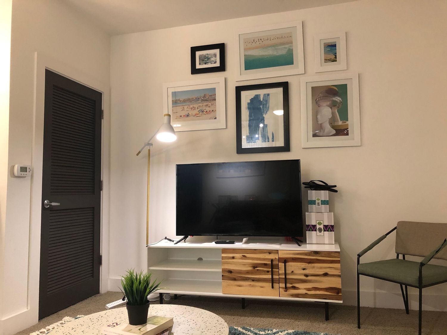 Modern living space with wall art, mounted TV, and wooden accent furniture.