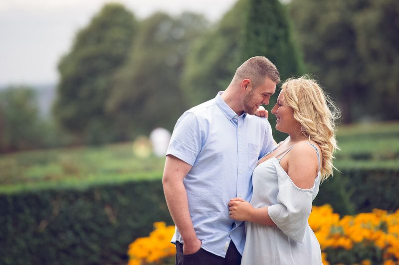 Intimate moment between couple near garden with bright orange flowers in background.