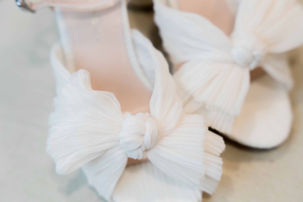 Elegant white bridal shoes with oversized tulle bow detail.