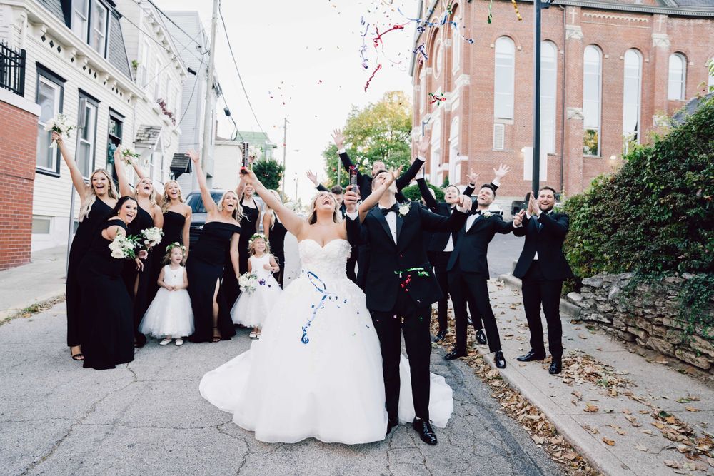 Wedding party celebrating on urban street with confetti toss.