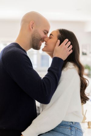 couple smiling super close to each other as he tucks her hair behind her ear