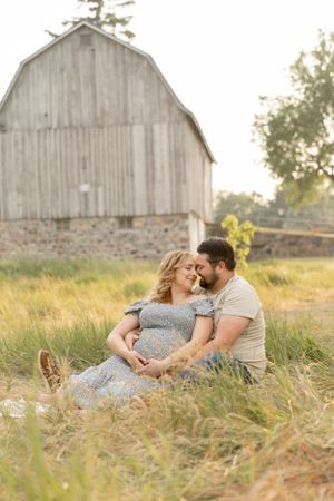 pregnant couples laying in a field in front of a barn in troy Michigan