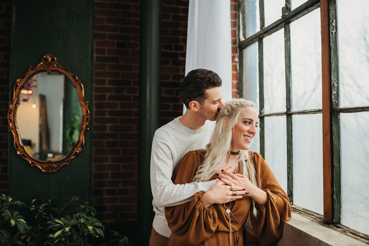 Engaged couple looking out window in Akron Ohio captured by Jessica Hepp Photography