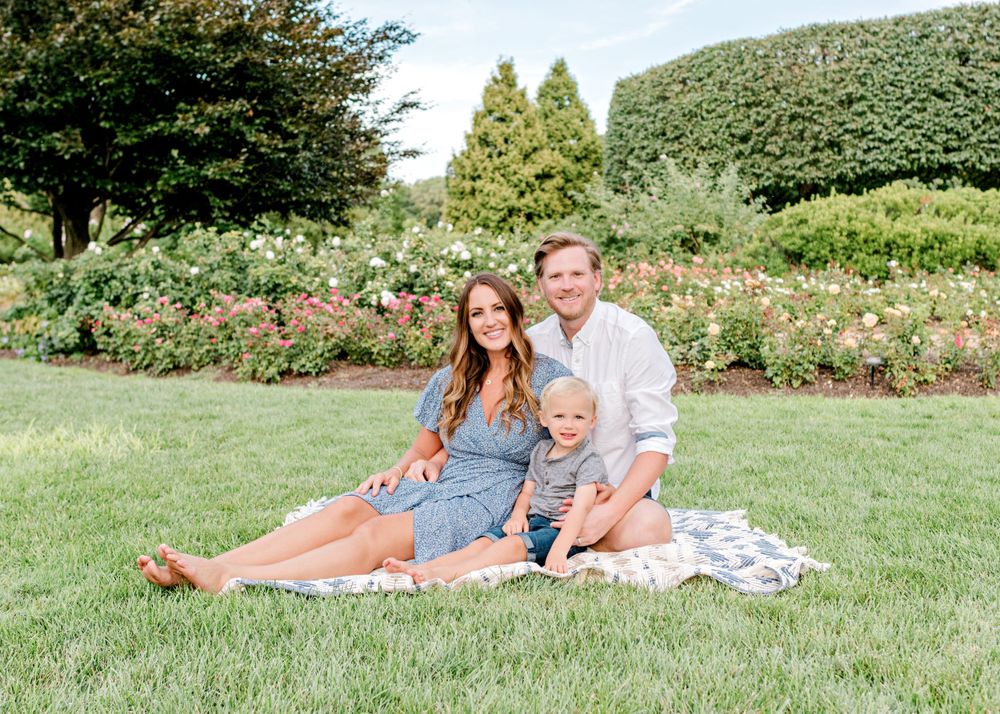 A family enjoys a picnic together in a beautiful rose garden setting.
