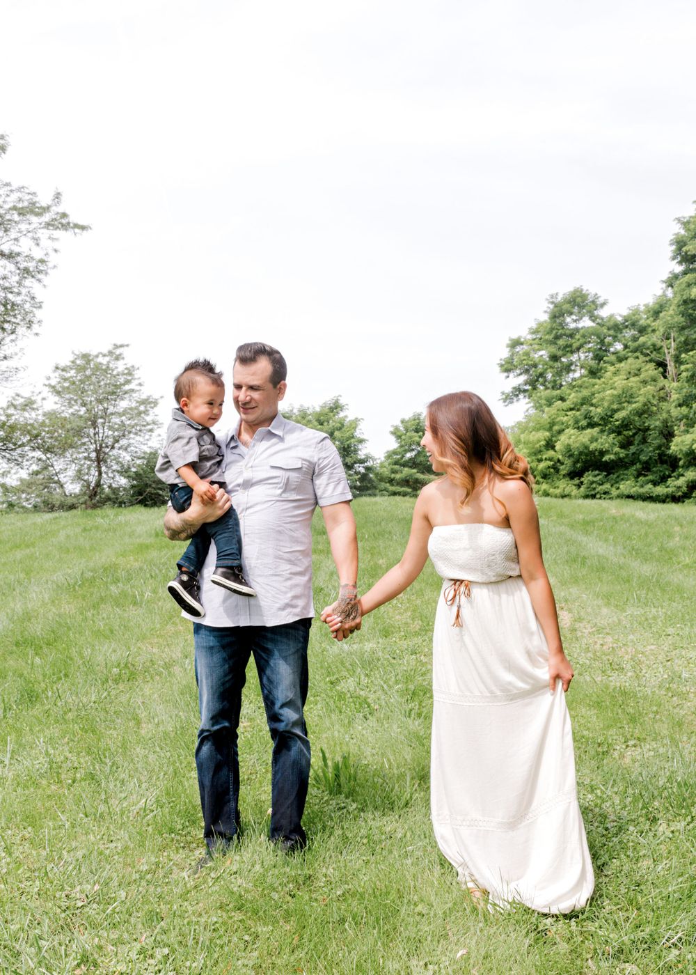 A family walking together through a sunny green field on a summer day.