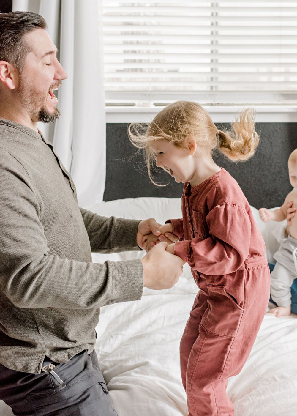 A playful family moment captured indoors with natural window light and joyful expressions.