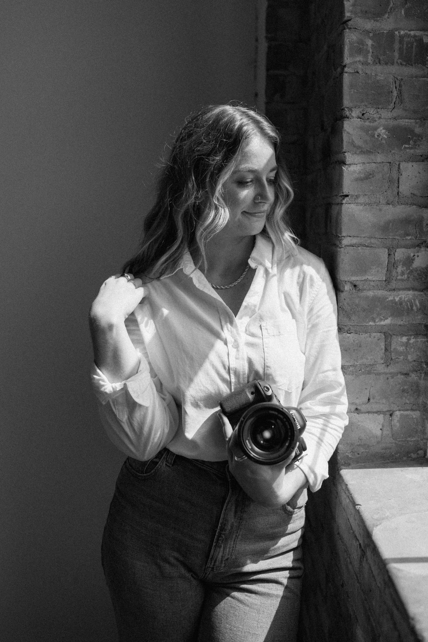 destination wedding photographer posing with camera in studio