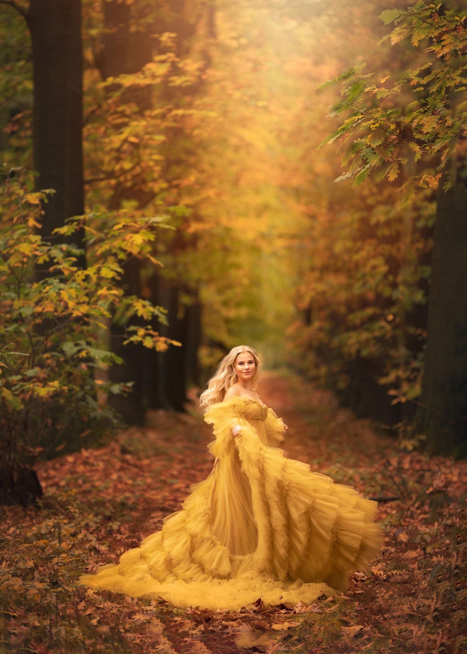jonge blonde vrouw, dansend door door een gouden herfstbos in een goudkleurige glamour jurk