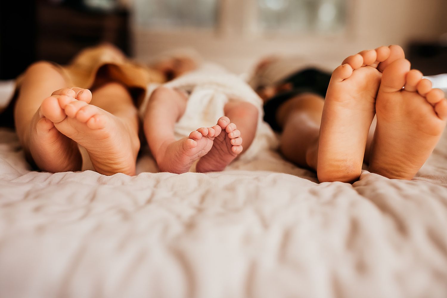 An image of all three siblings feet while laying on the bed.