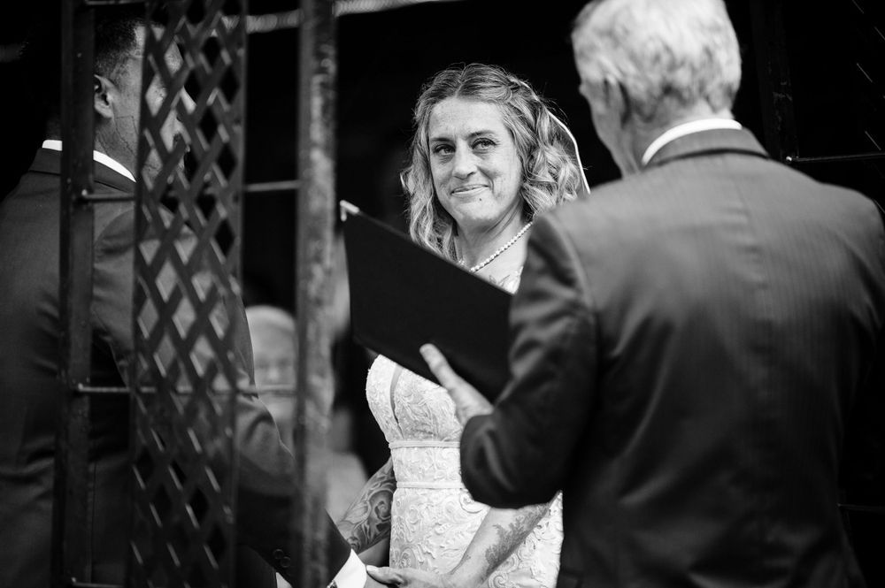 Black and white candid photograph of intimate wedding ceremony conversation.