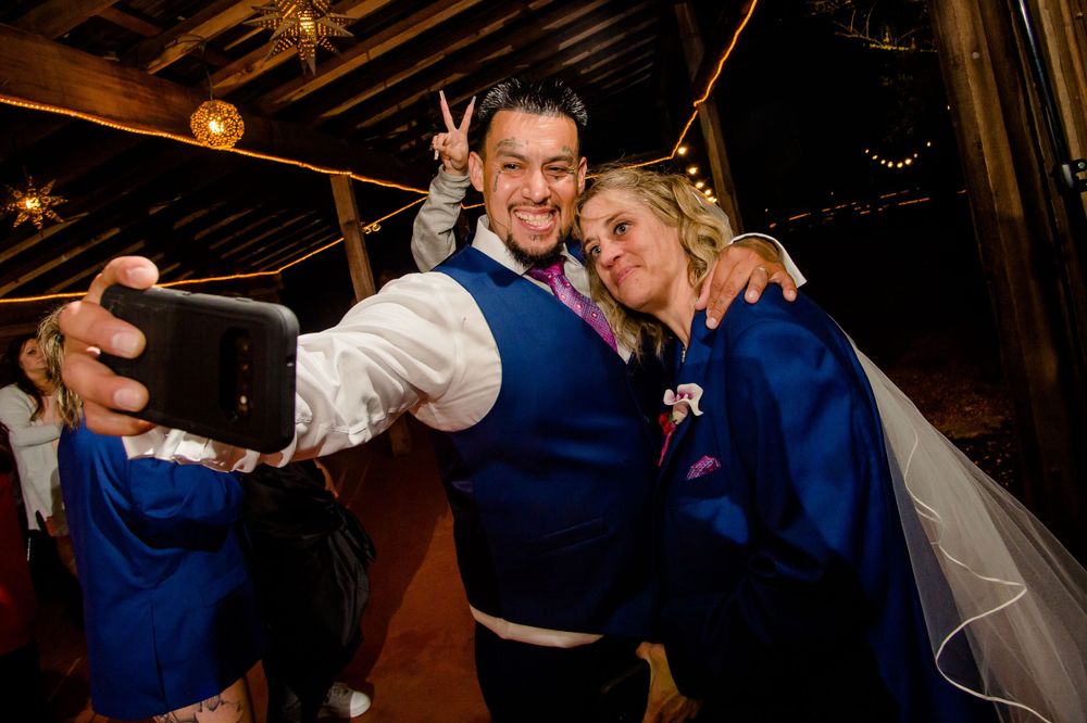 Wedding celebration selfie moment in blue attire at indoor reception.