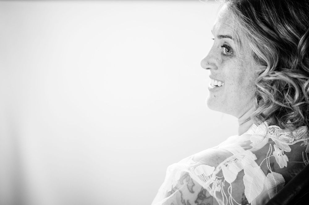 Black and white profile portrait of a woman with curly hair smiling against a light background.