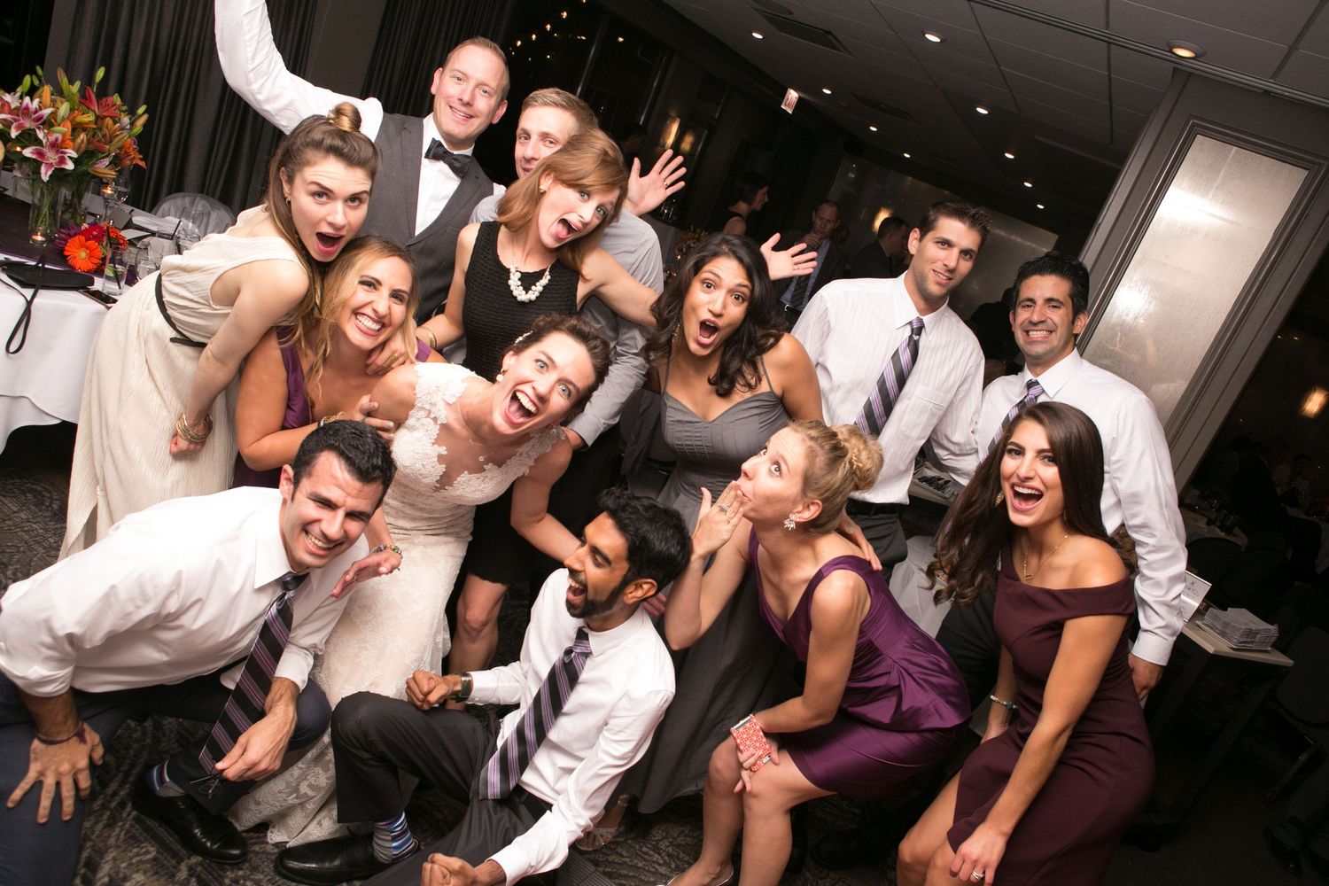 A lively group of wedding guests poses together on the dance floor during reception celebrations.