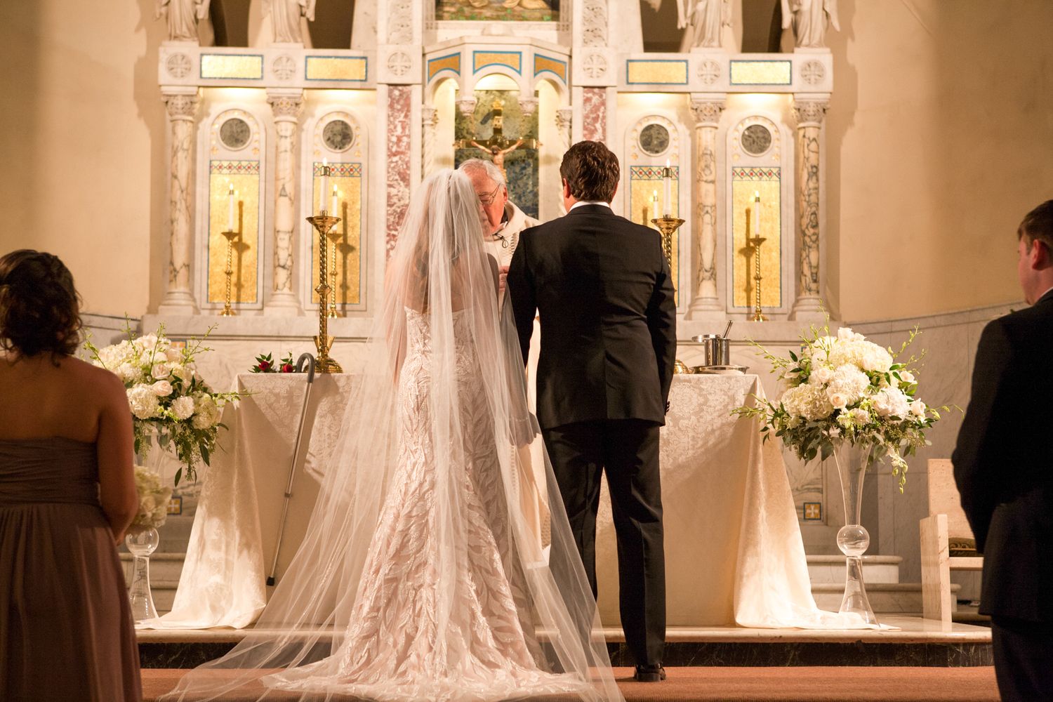 Ornate cathedral altar decorated with white flowers and candles for elegant wedding ceremony.