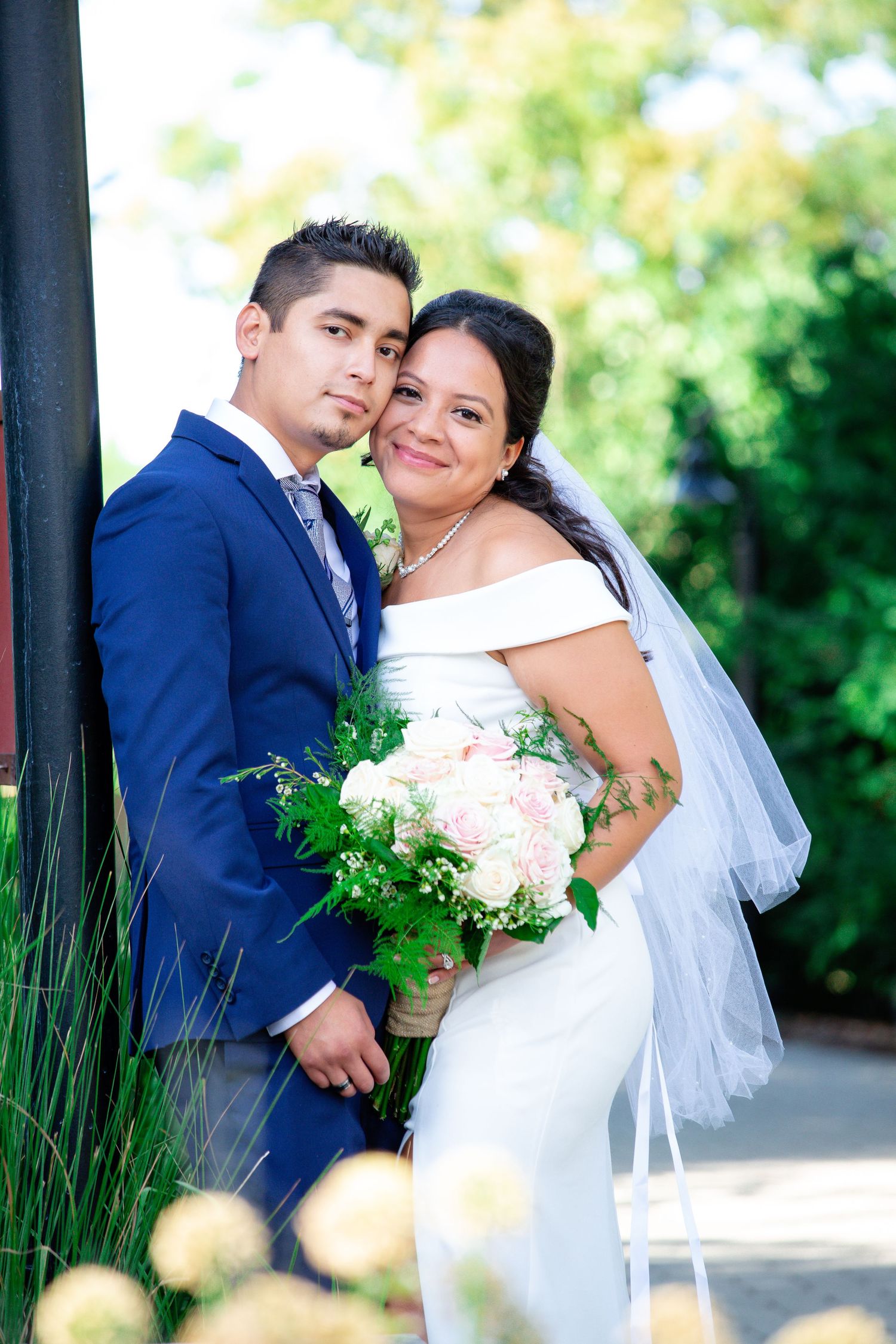An intimate wedding photo with beautiful garden scenery and pink bouquet.