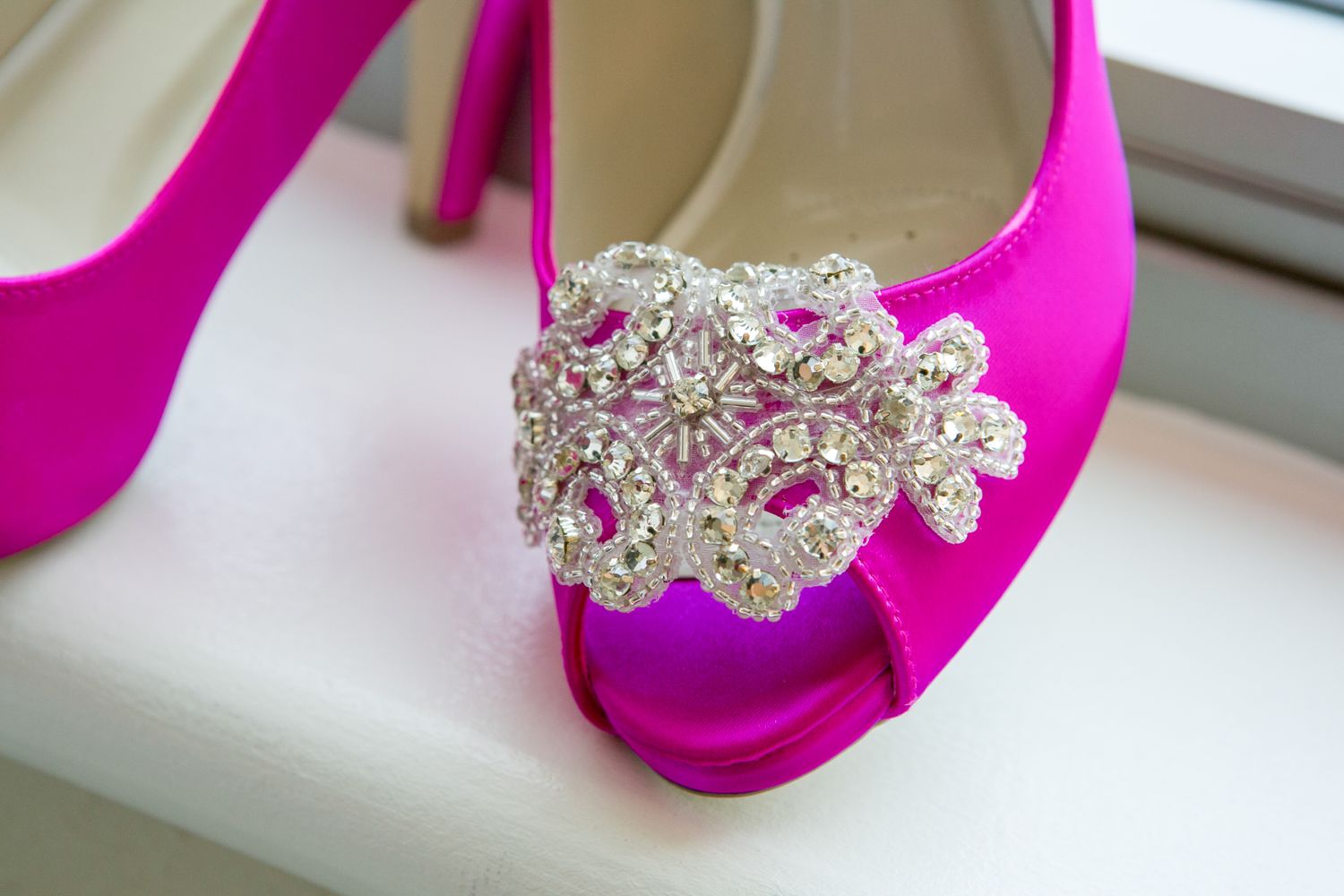 Hot pink satin peep-toe heel with crystal brooch detail.