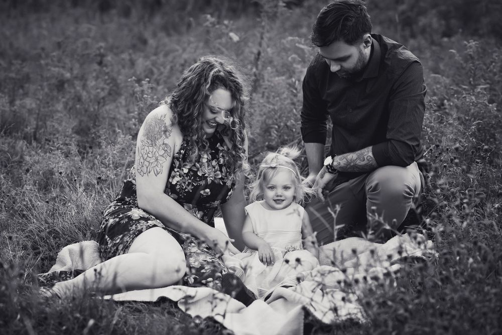 beautiful black and white photo of small family in a field sitting on a blanket
