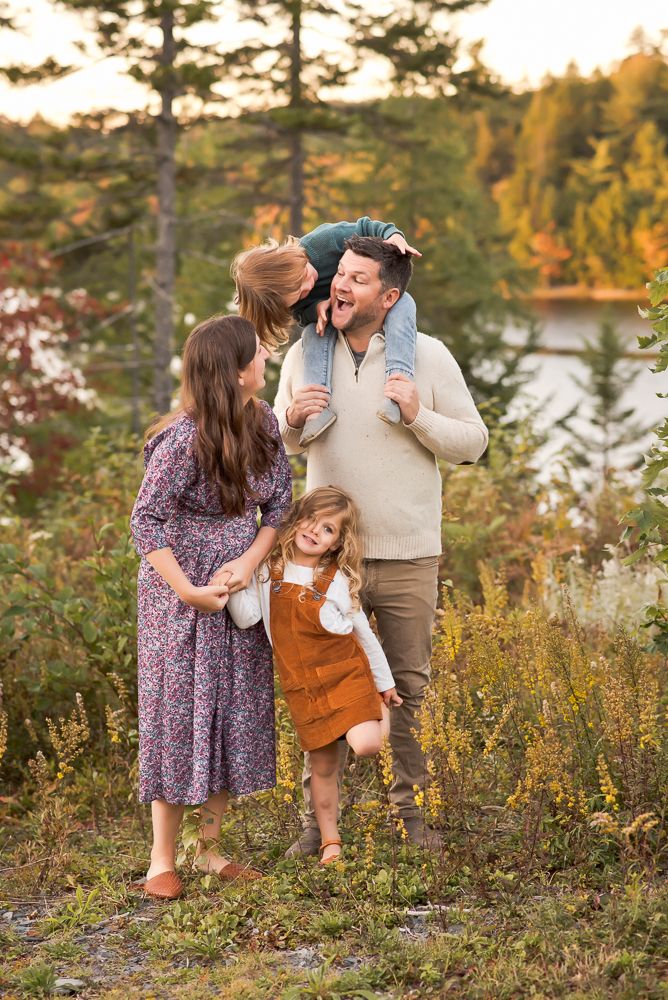stunning family of 4 in a lake setting with little boy on dad shoulders and little girl holding mom's hand