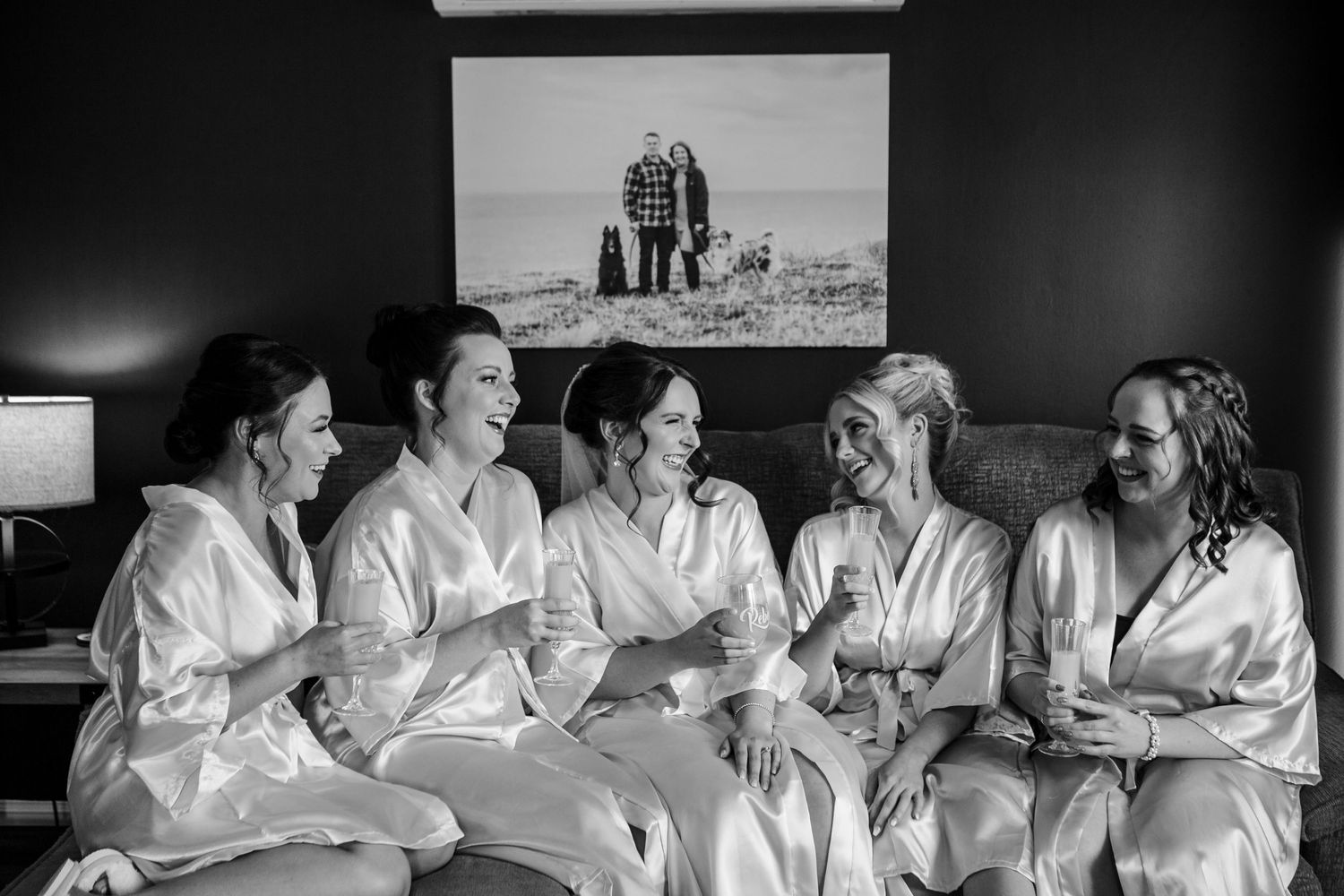 Black and white photo of bridal party lounging together in matching robes.