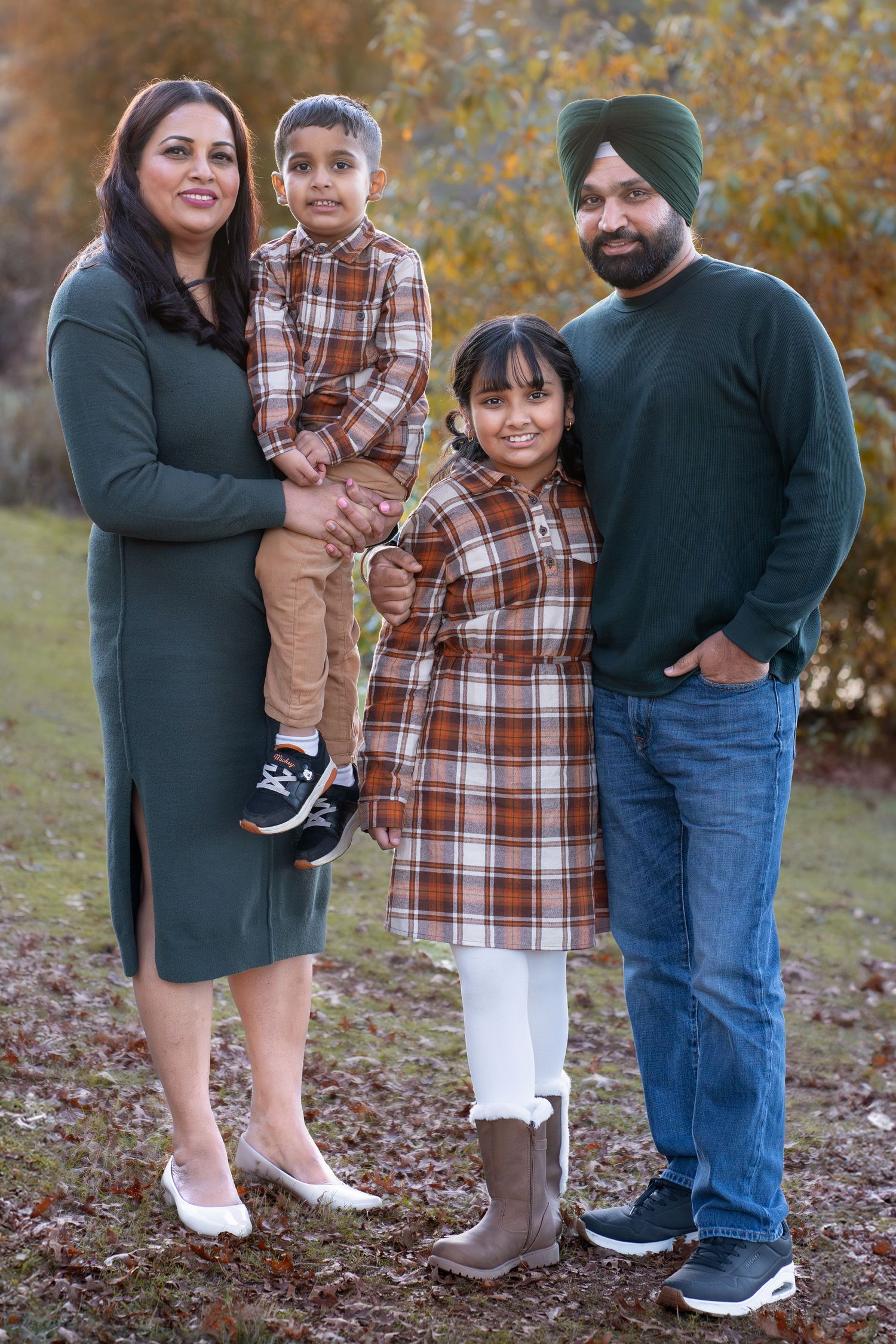 A family in matching plaid outfits poses together during fall season.