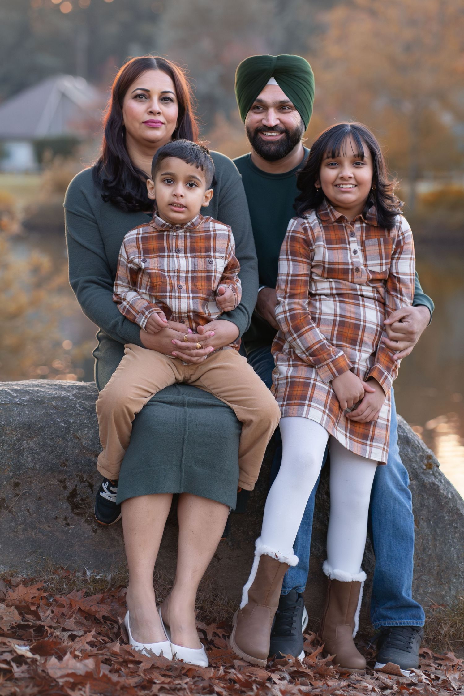 A family in coordinated outfits poses together on rocks during autumn.