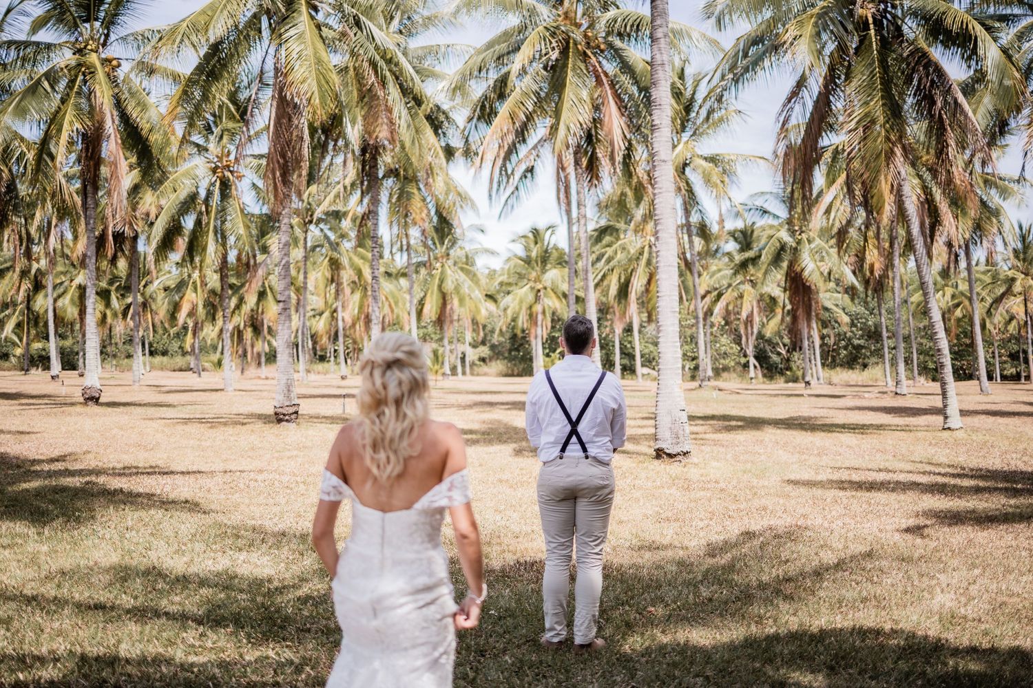 Newlyweds walk through a tropical palm tree grove on their wedding day.
