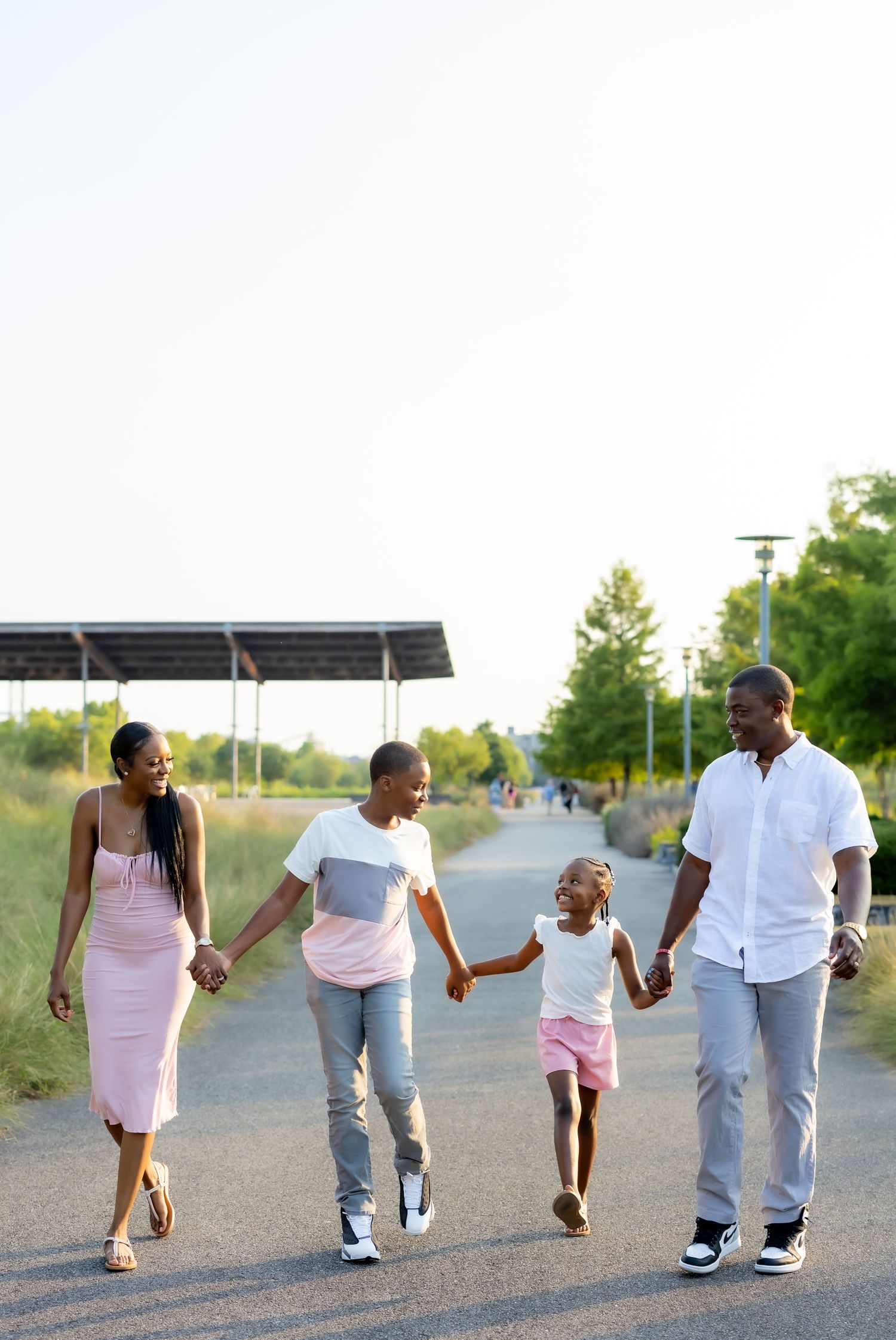 A group walks hand in hand down a paved road at sunset.