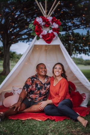 Outdoor family photoshoot with white tent decorated with red flowers.