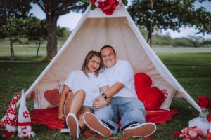 A romantic outdoor photo session with a white teepee tent and red rose decorations in a park setting.