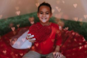 Decorative red heart bokeh lights create a romantic atmosphere during an outdoor photo session.