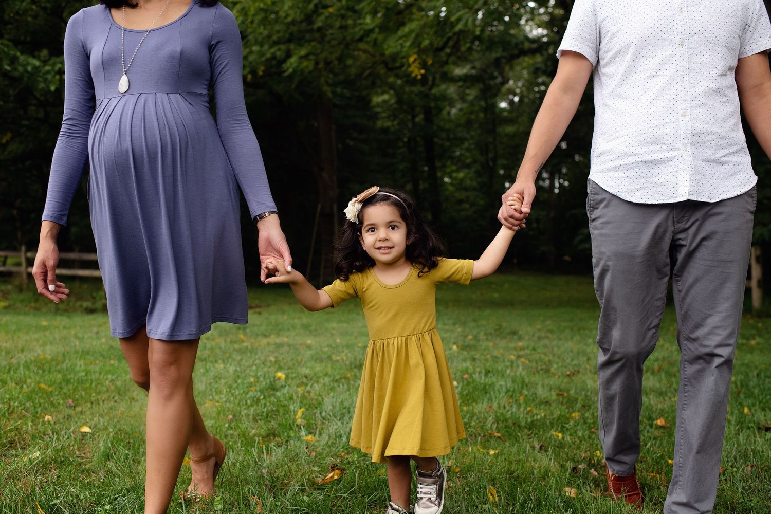 outdoor maternity in green meadow walking and holding hands