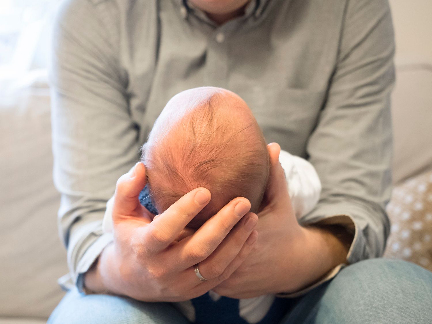 A father cradles his new baby in his hands