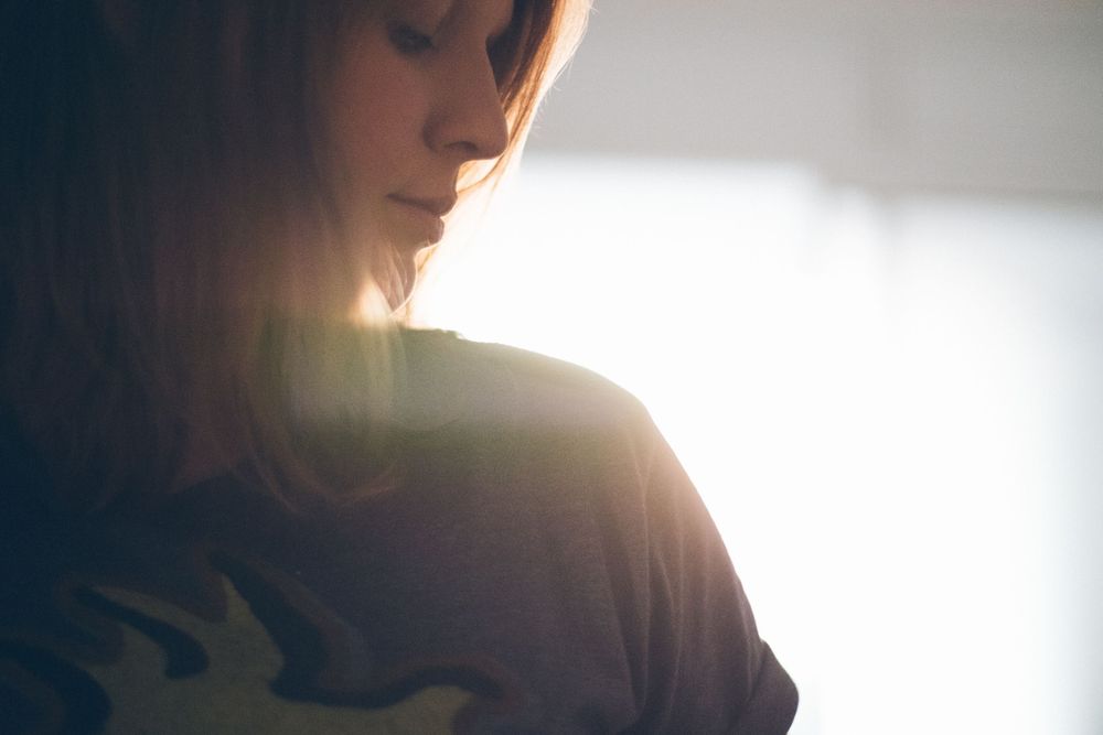 Silhouette profile against window light showing shoulder and graphic t-shirt design.
