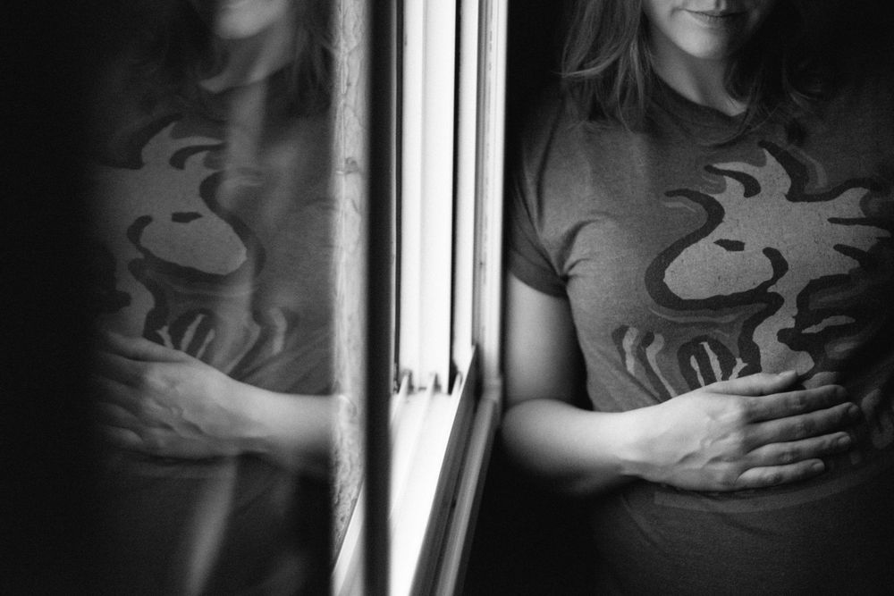 Artistic black and white reflection showing pregnant person in graphic t-shirt.