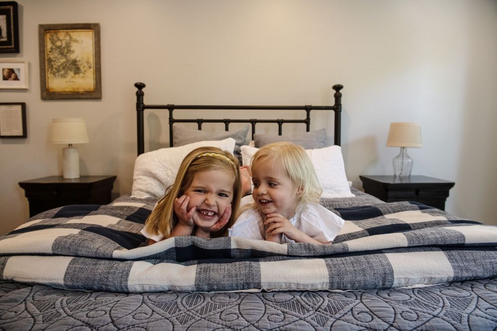 Intimate family photos taken on a bed with dark metal headboard.