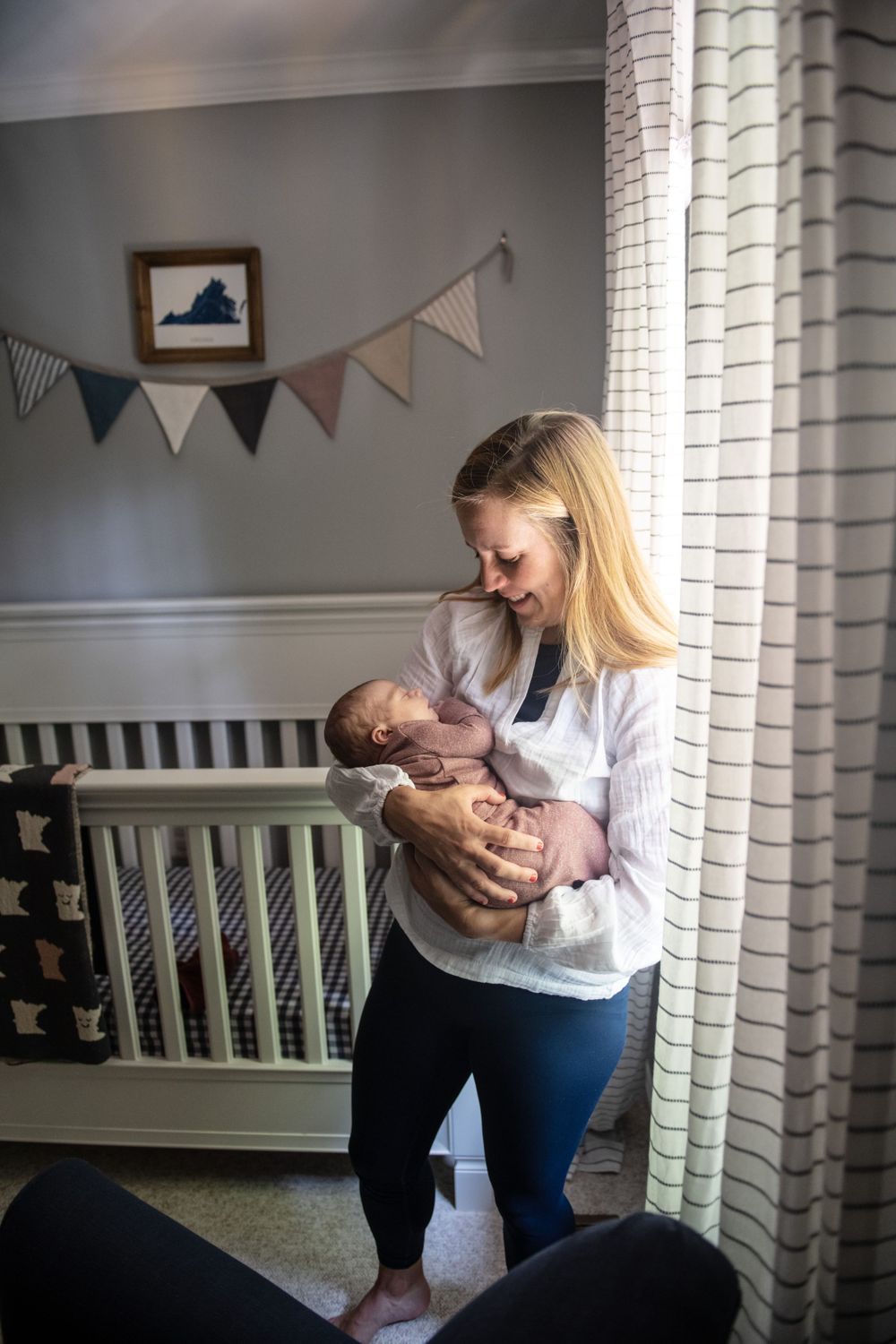 A nurturing scene in a nursery with decorative bunting as a caregiver holds a sleeping baby.