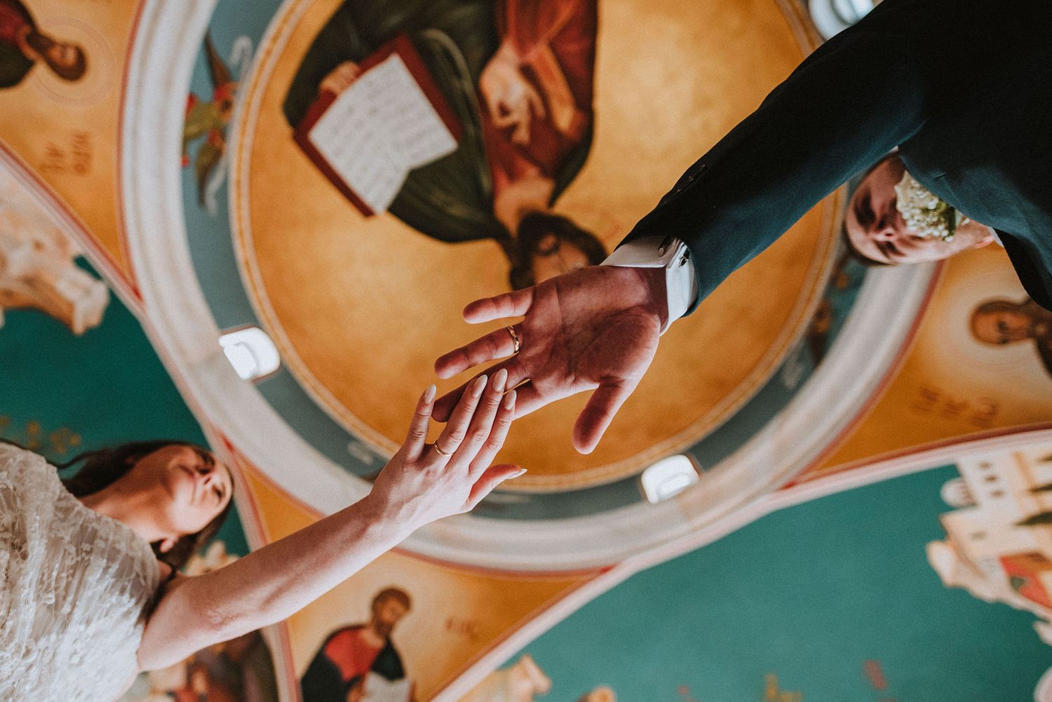 Close-up view of hands exchanging rings during an orthodox church wedding ceremony.