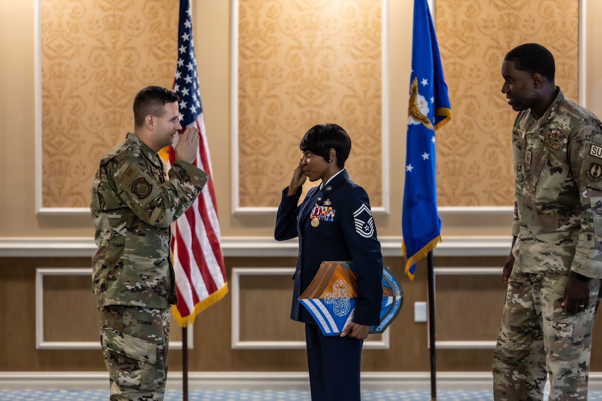 Military personnel conduct official ceremony with salute in front of American and Air Force flags.
