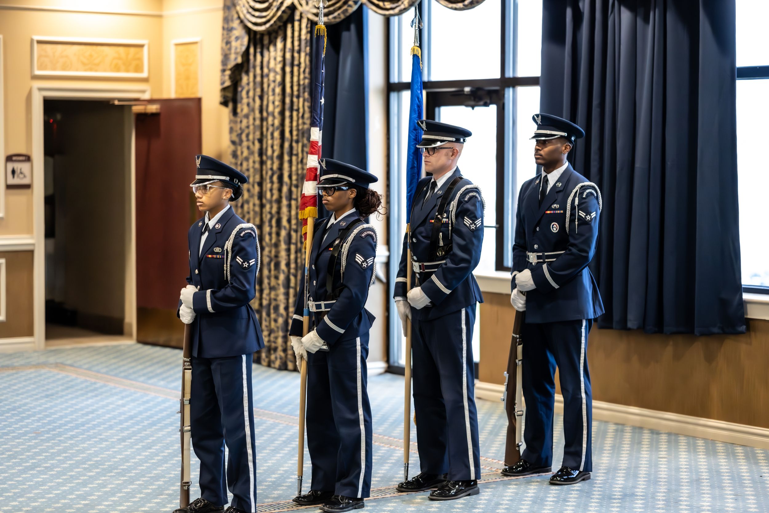Honor guard members stand at attention in dress uniforms during formal ceremony.