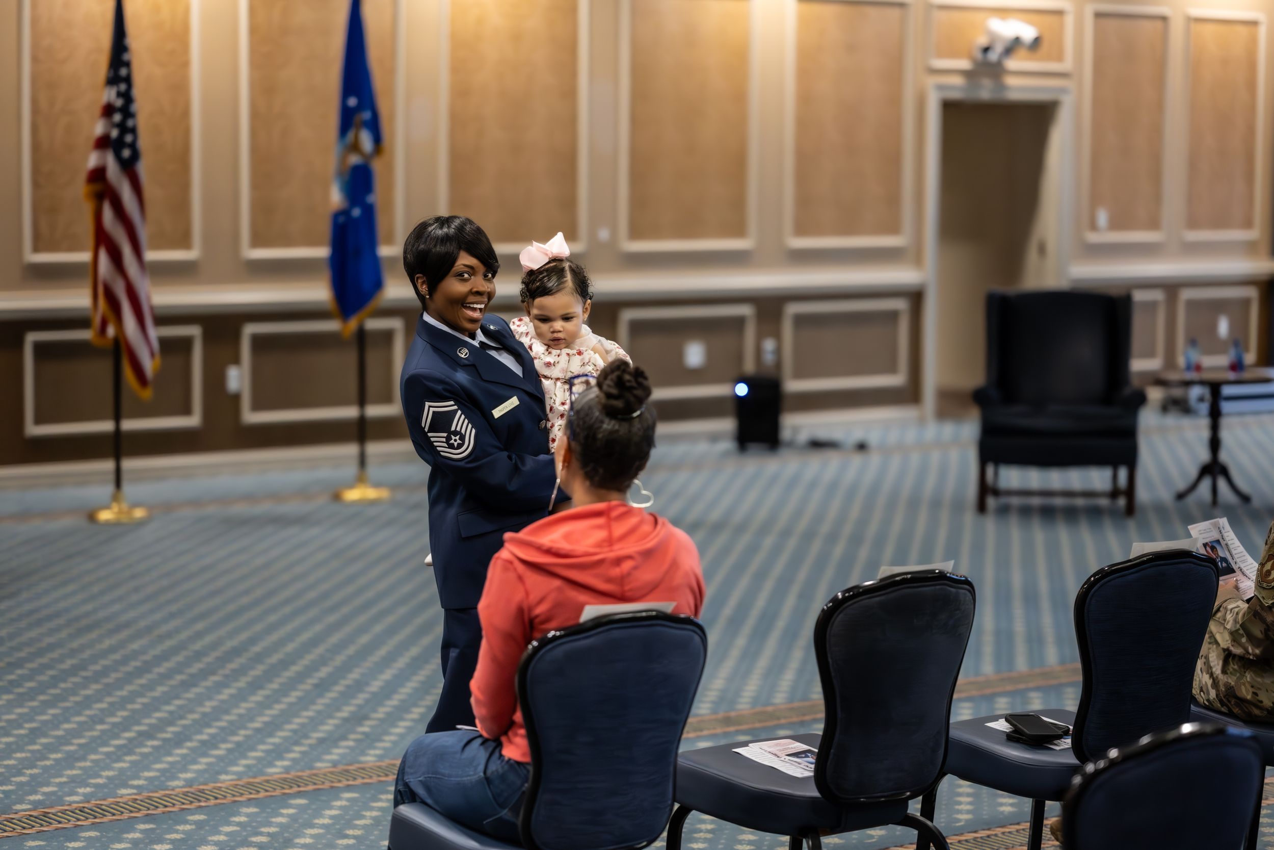 Service members assemble in formation during an indoor military ceremony.