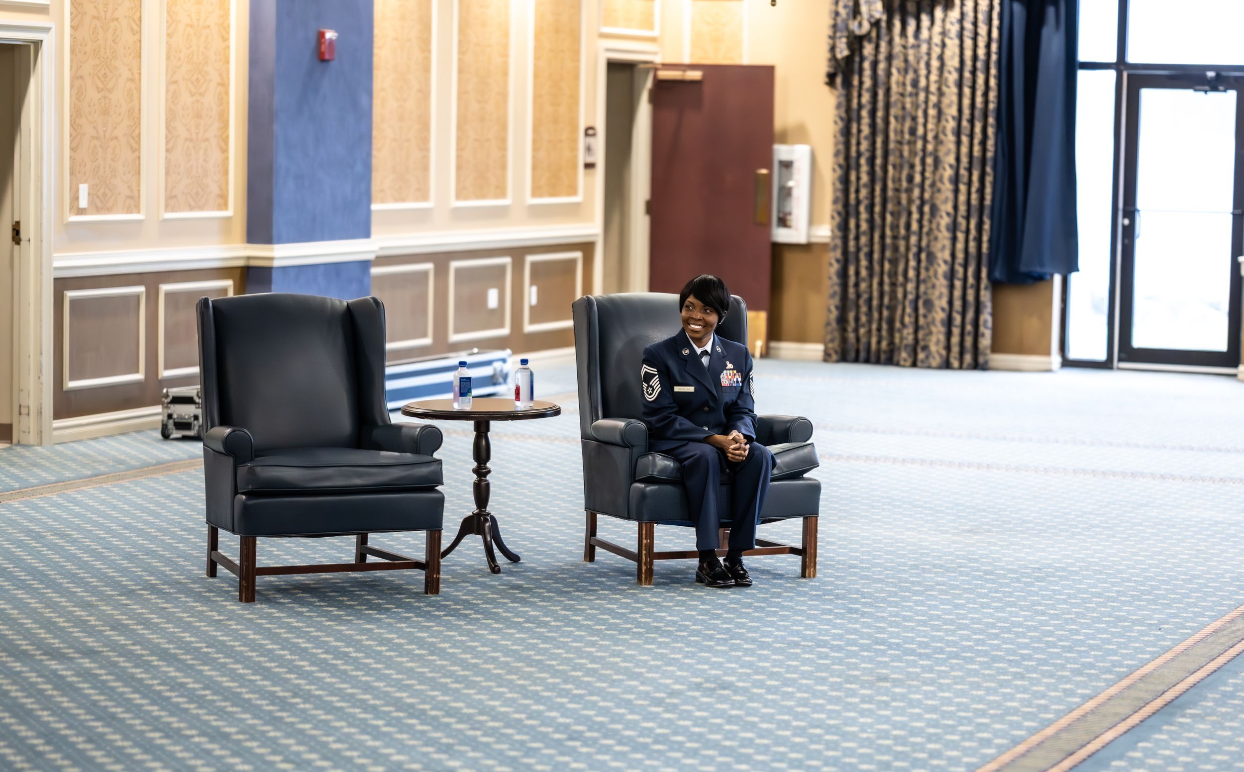 Empty chairs and podium arranged in a formal conference room with American flag displayed.
