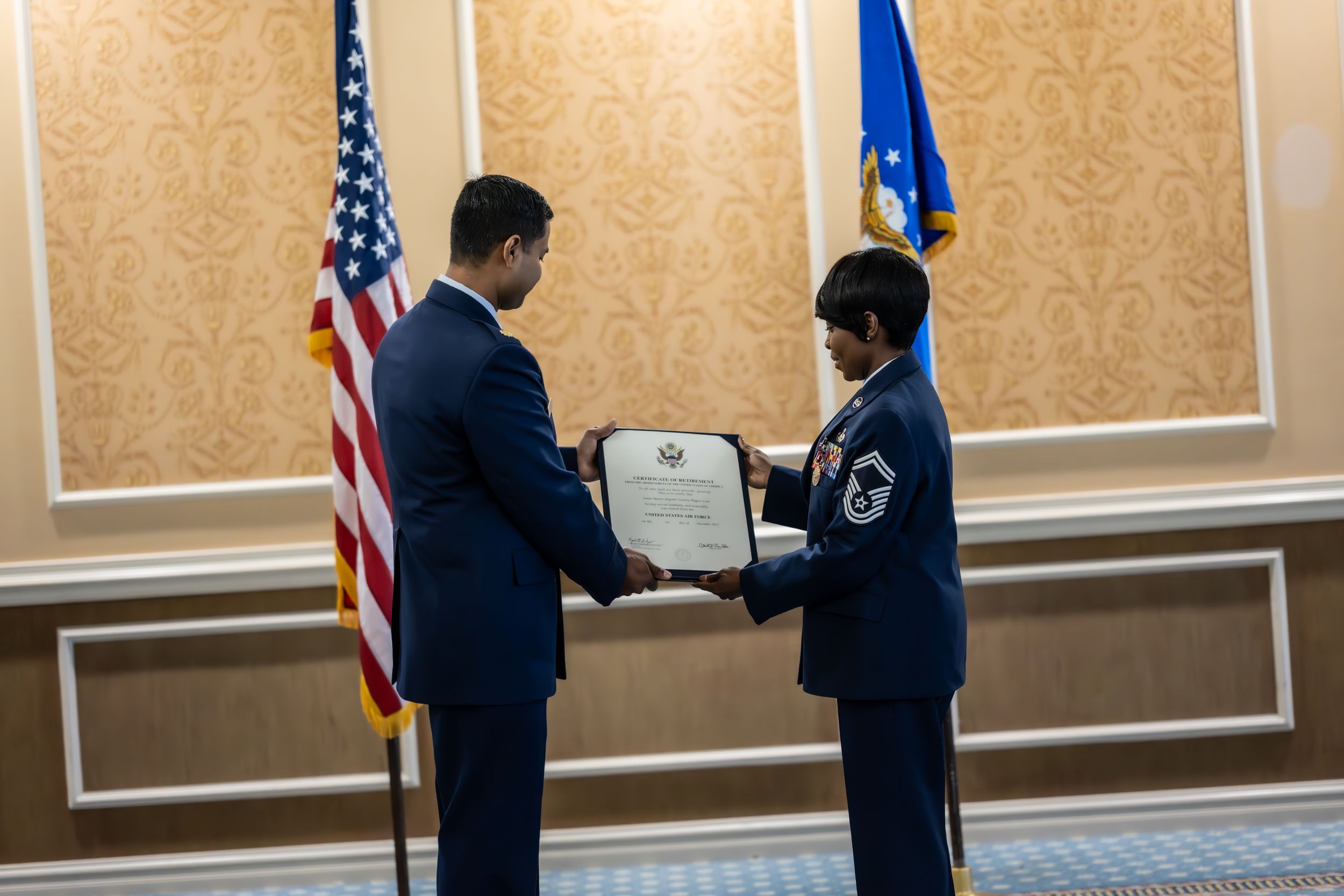 Service members participate in award ceremony with American and state flags as backdrop.