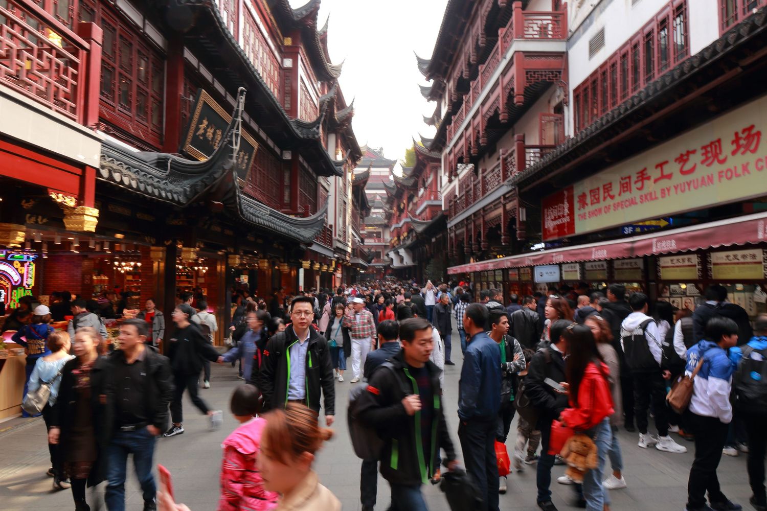 Crowded traditional shopping street in Shanghai's Yu Garden area with historic architecture.