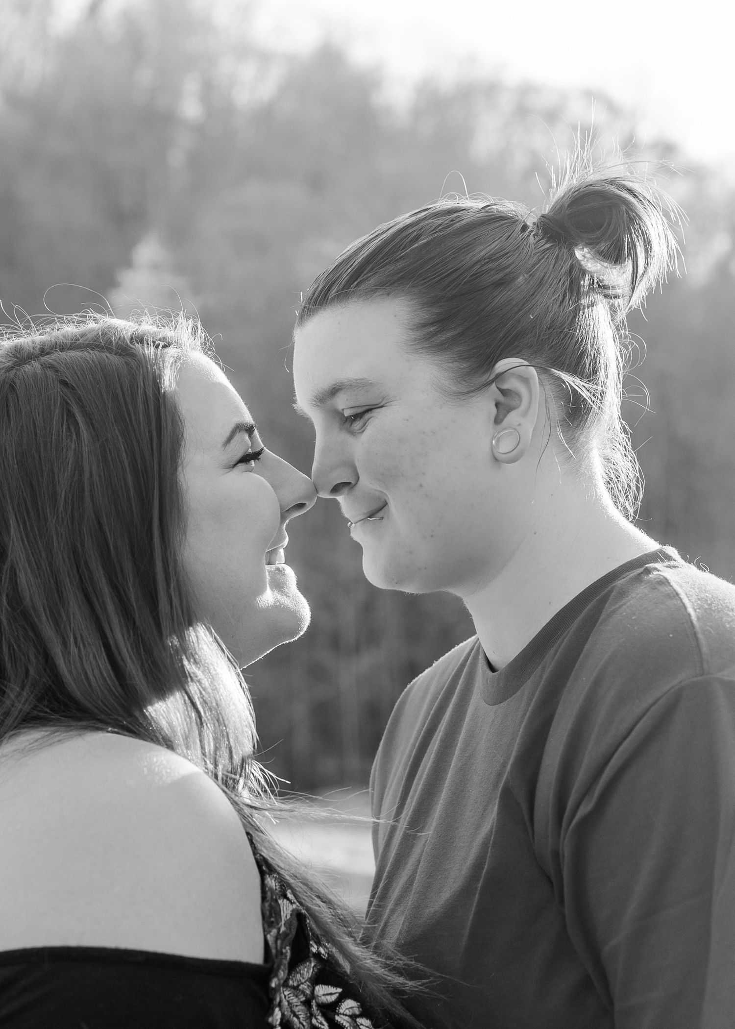 A romantic black and white portrait of a couple sharing an intimate moment outdoors.