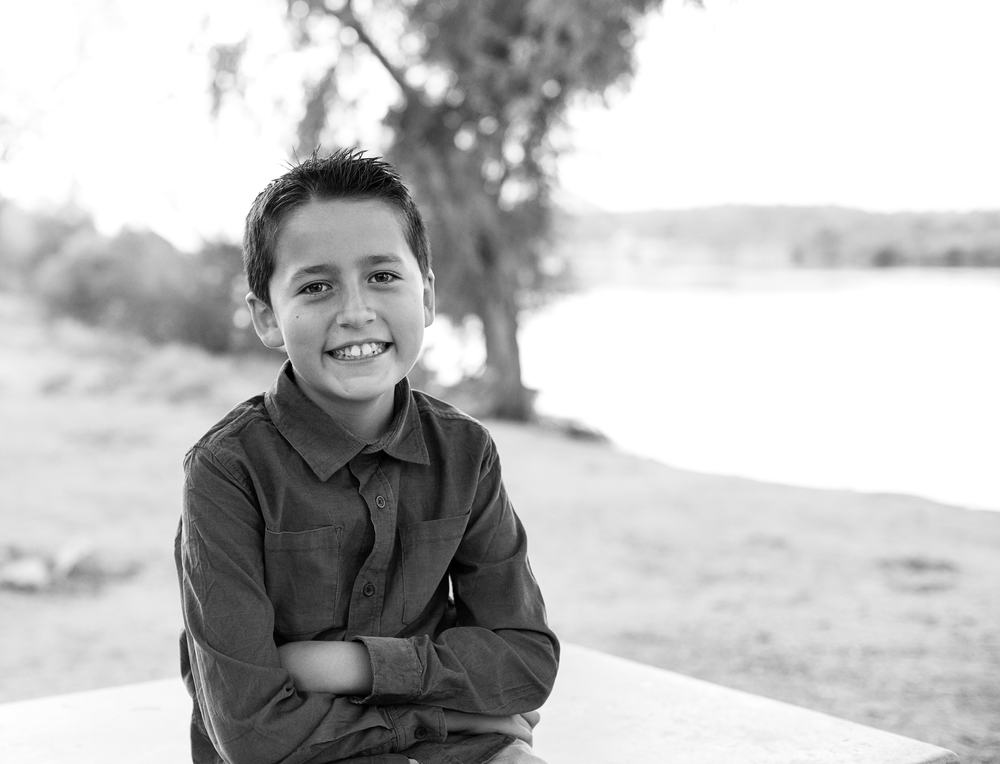 Black and white portraits of children sitting outdoors in natural lighting.